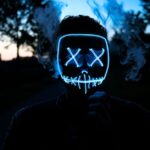 Een vrouw gebruikt een LED gezichtsmasker voor huidverbetering en ontspanning thuis, om acne en rimpels te verminderen.
