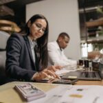 Een professional die een zakelijke rekening opent met een laptop en papieren, symboliserend voor financiële organisatie.
